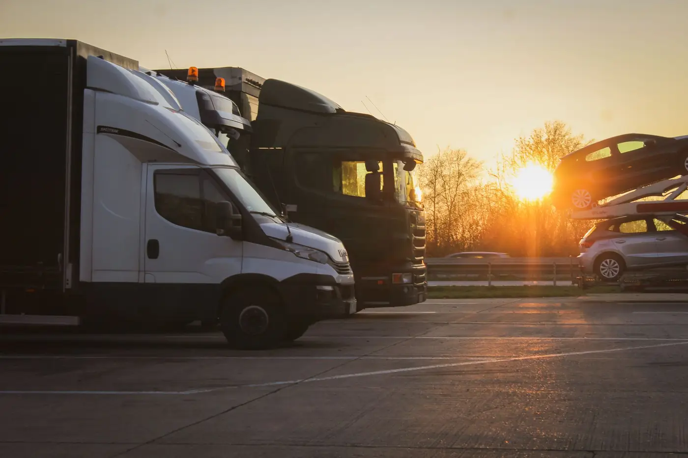 Geparkeerde voertuigen op een parkeerplaats langs de weg bij zonsondergang
