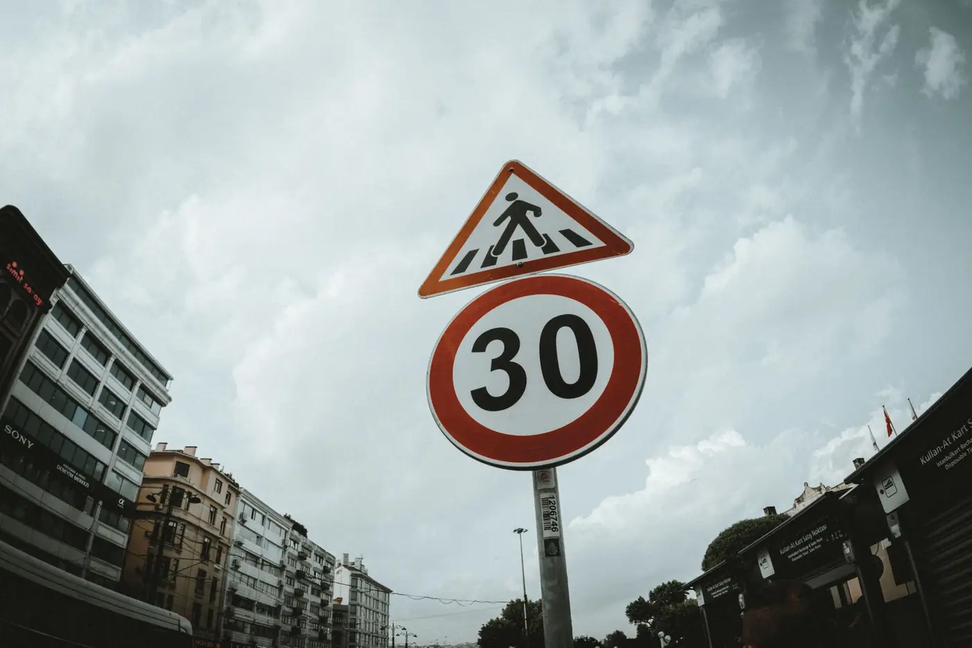 Verkeersbord met snelheidslimiet langs een straat onder een bewolkte hemel