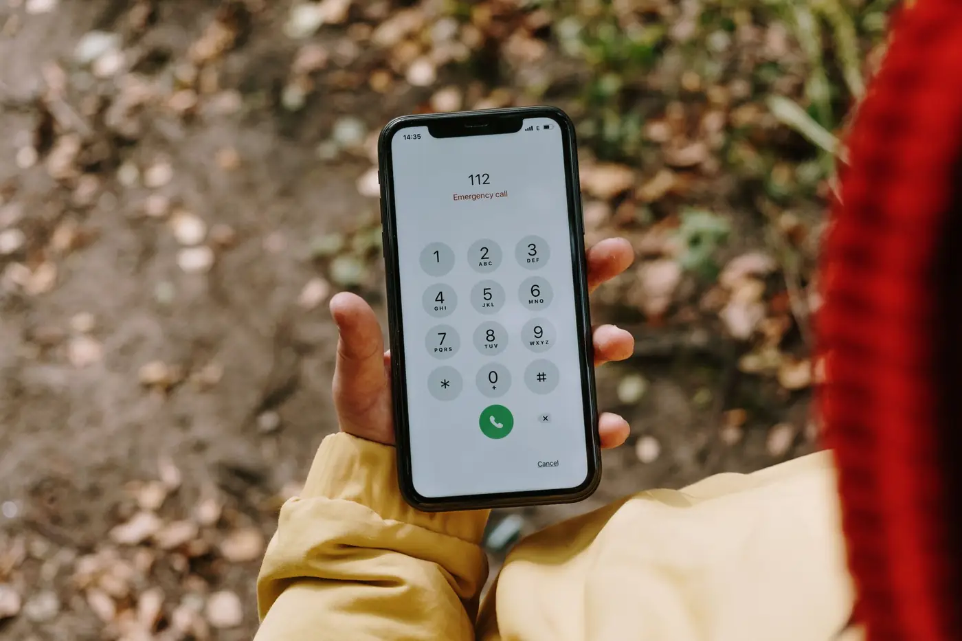Hand houdt een smartphone vast met een noodnummer op het scherm