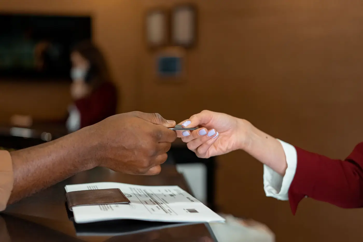 Hotelreceptioniste neemt een betaalpas aan van een gast bij het inchecken