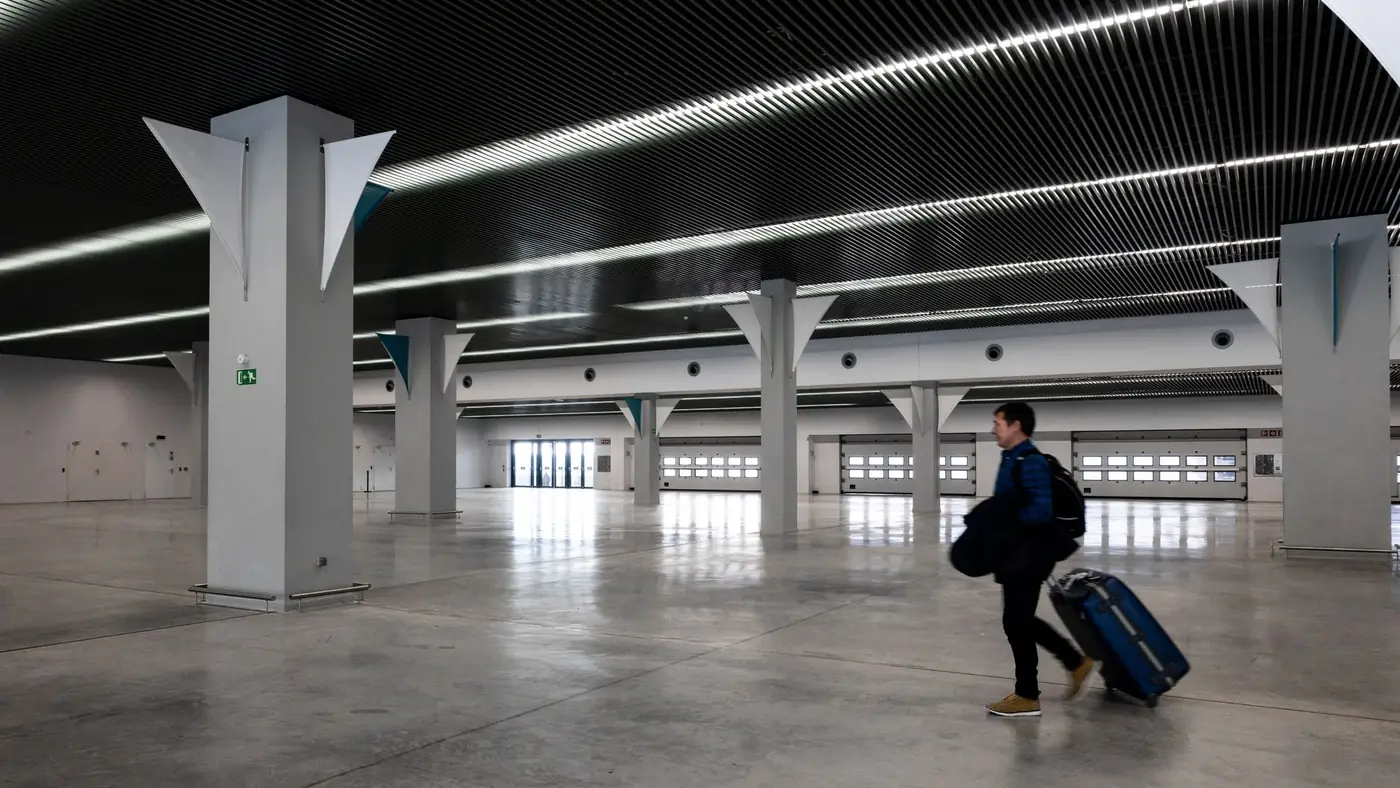 Reiziger met bagage loopt door een ruime, moderne luchthavenhal