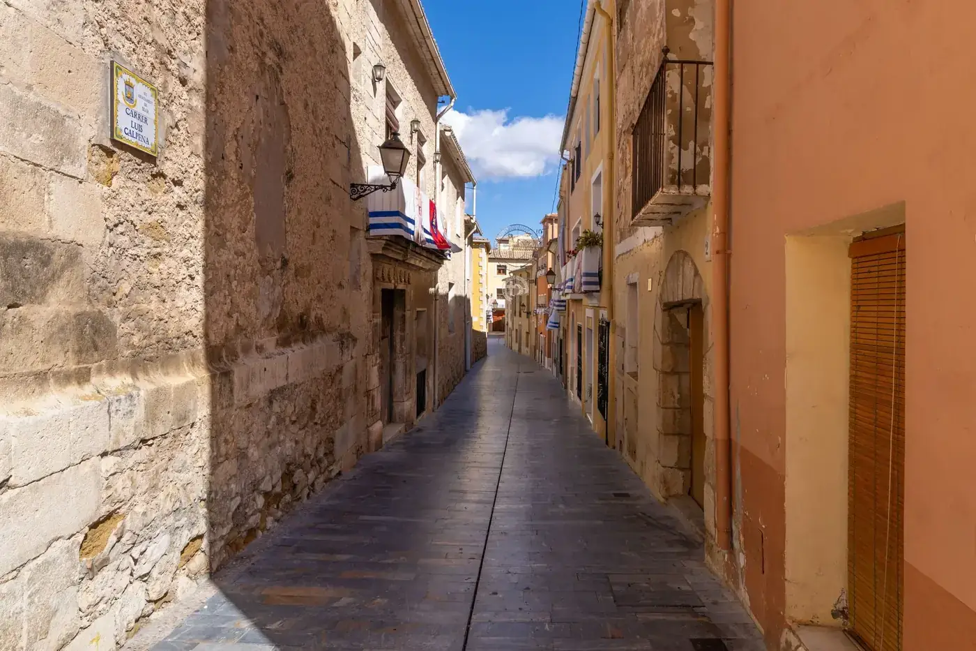 Picturesque narrow street with historic stone buildings in Biar, Comunidad Valenciana, Spain on a sunny day.