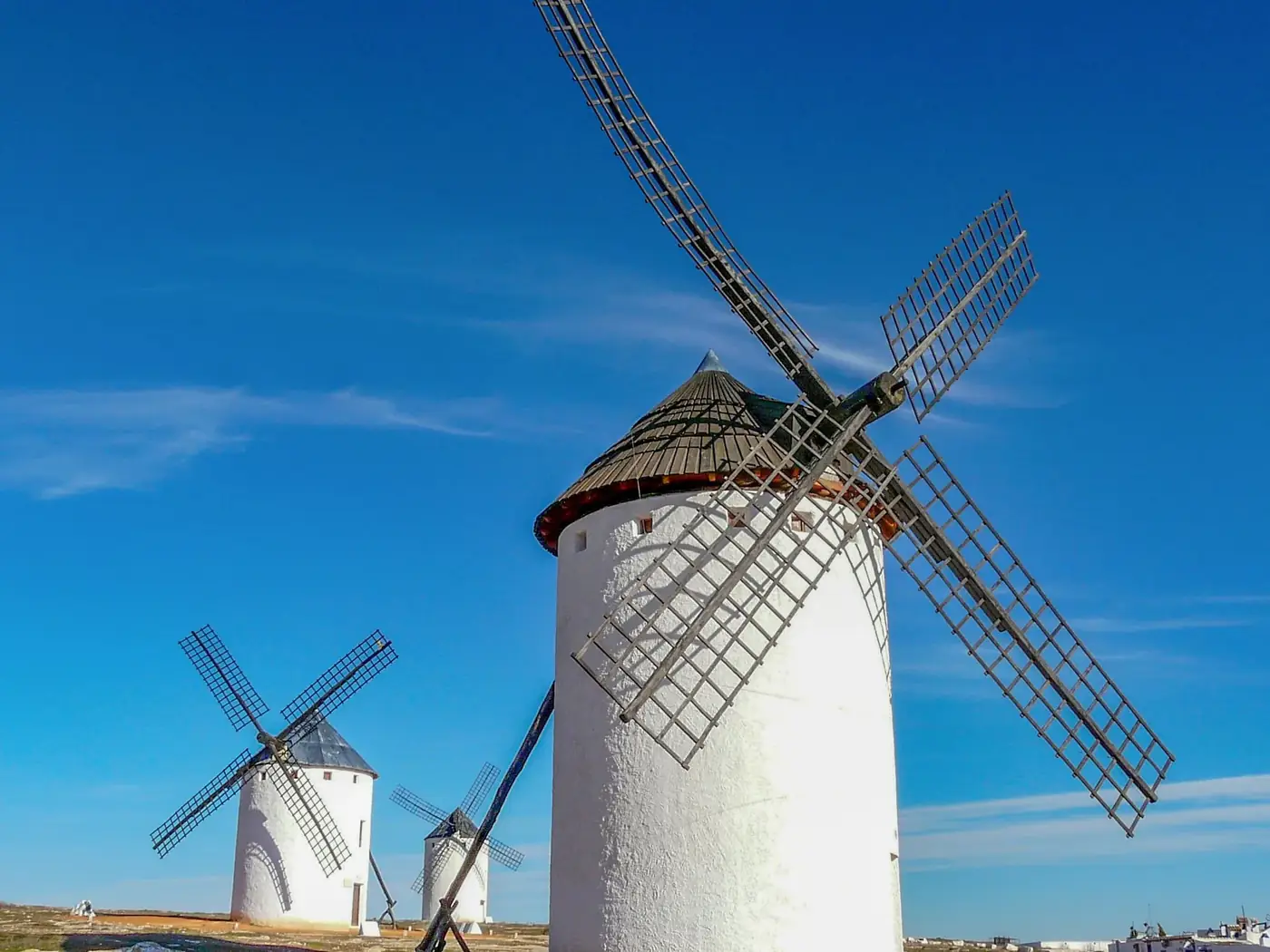 Iconic white windmills against clear blue skies in Campo de Criptana, Spain.