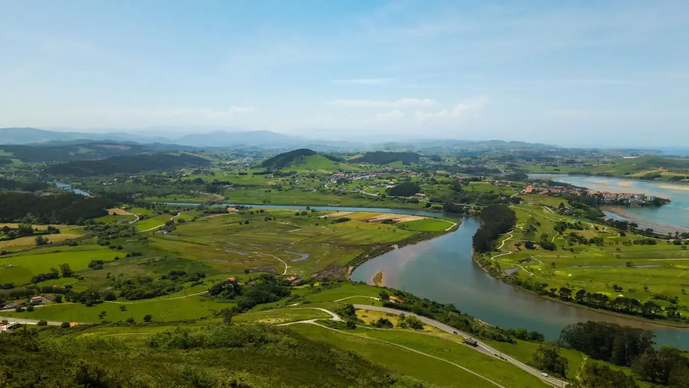 Scenic aerial view of the lush green landscape in Cantabria, Spain with a winding river.