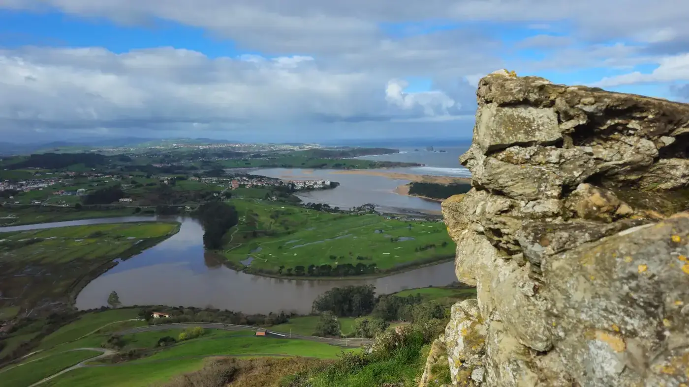 A stunning aerial view of Cantabria's natural landscape featuring rivers, greenery, and distant ocean.