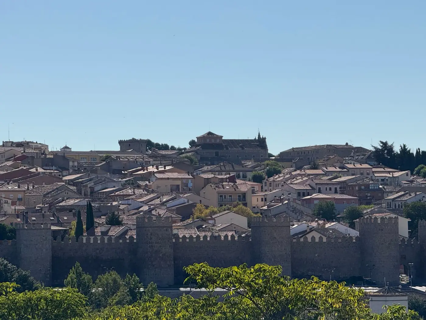 Panoramic view of Ávila's medieval walls under a clear blue sky.