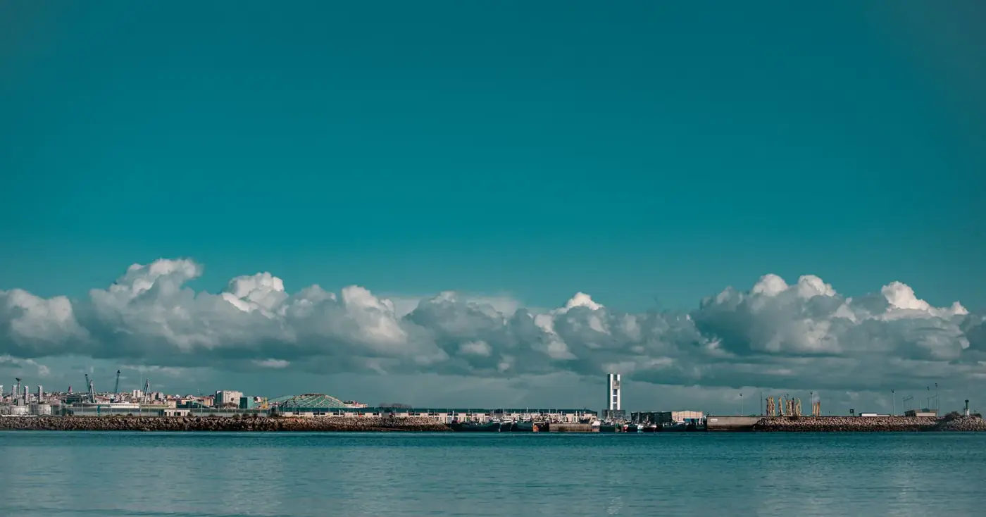 A scenic view of a coastal cityscape with fluffy clouds and calm sea.
