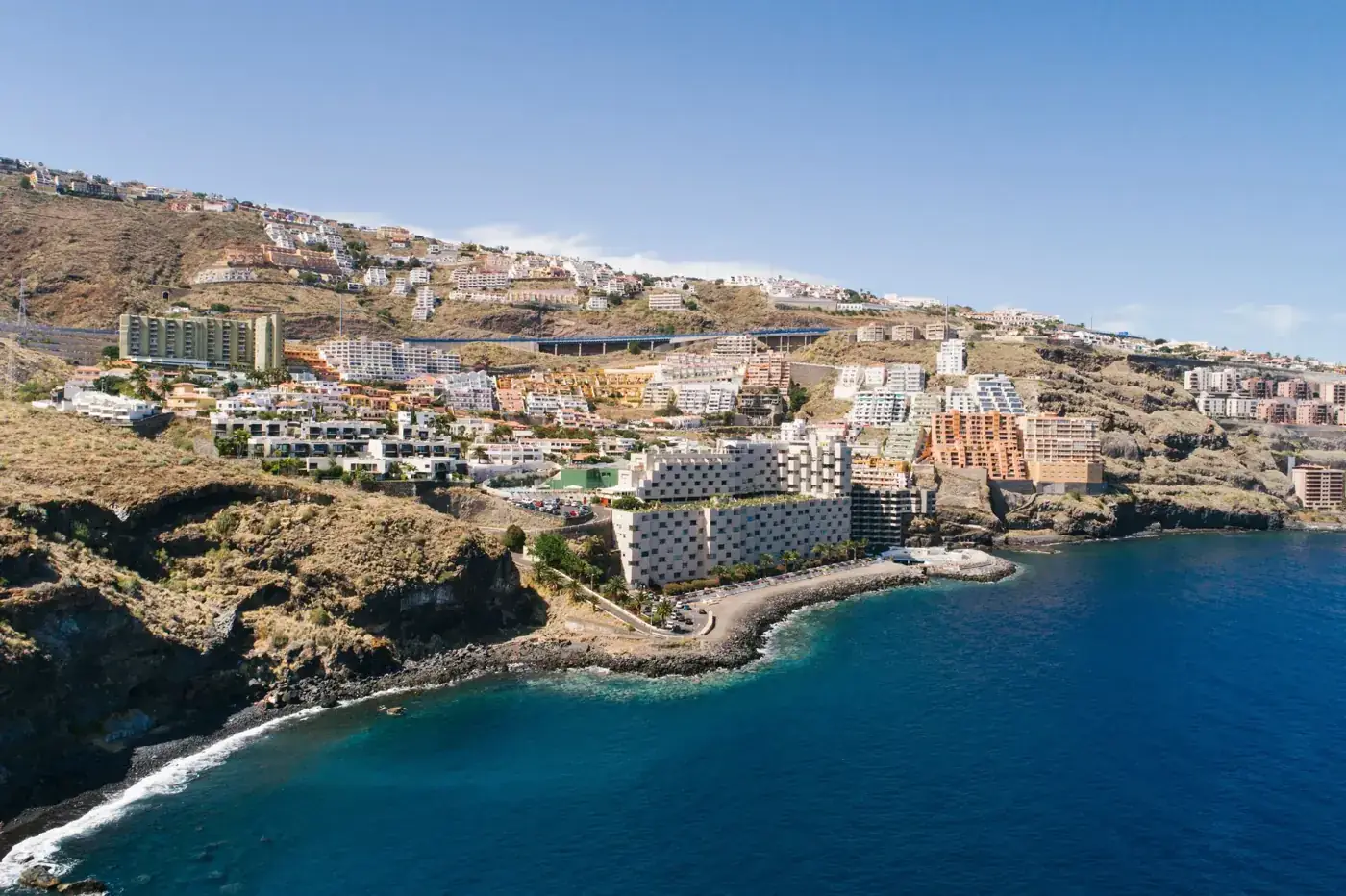 Stunning aerial view of Tenerife coastline with resorts and ocean under clear blue sky.