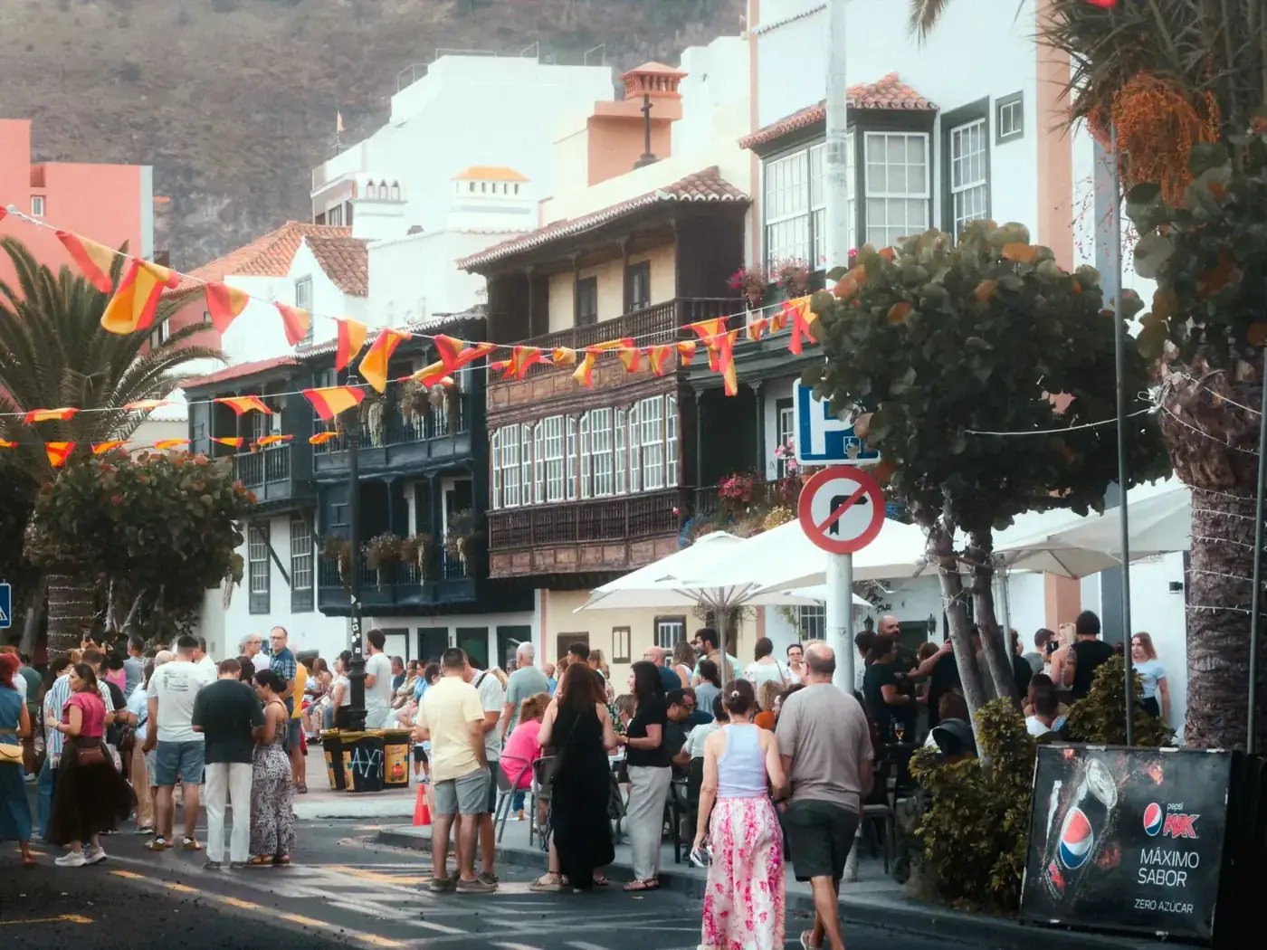 Crowds enjoying a lively street festival in La Palma, Spain with colorful decorations and historic architecture.
