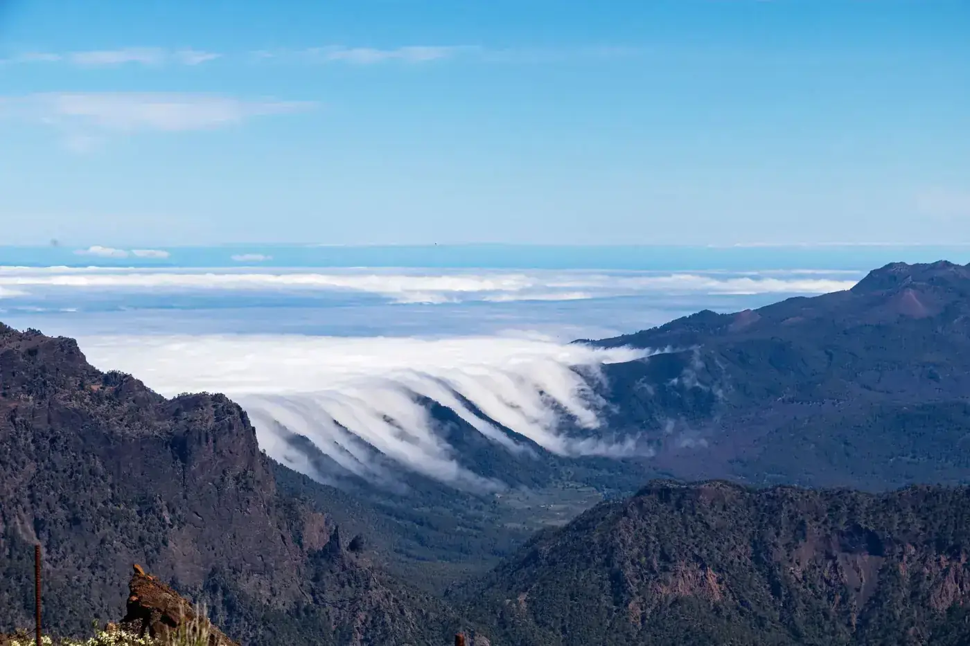 Dramatic view of La Palma's scenic mountains and rolling clouds under a clear blue sky.