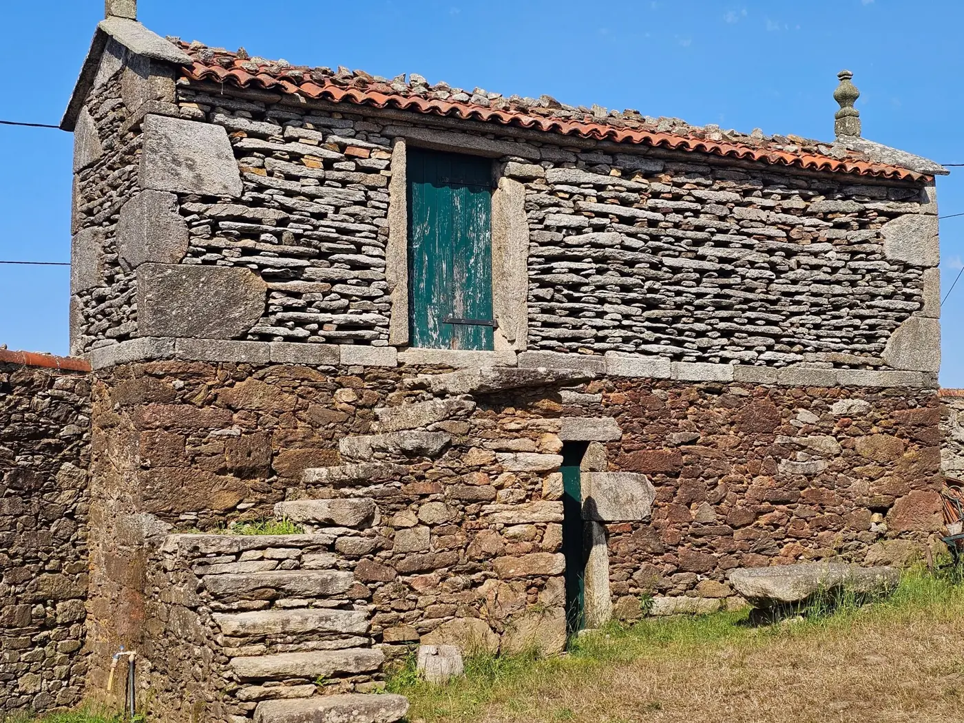 Traditional Galician stone hórreo under a clear blue sky in Spain.