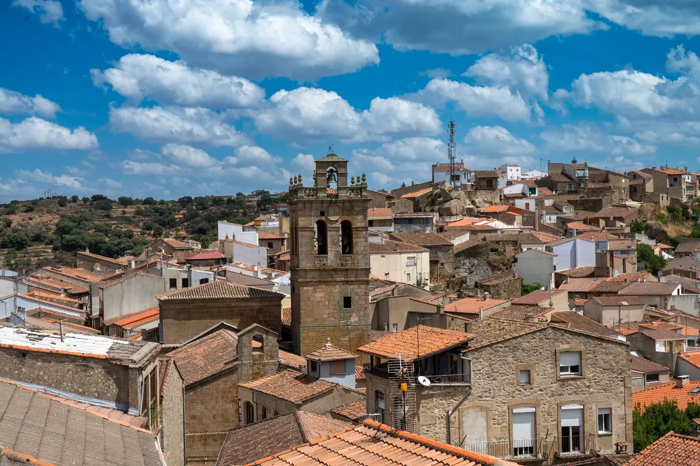 Picturesque view of a traditional Spanish village under a vibrant blue sky with scattered clouds.