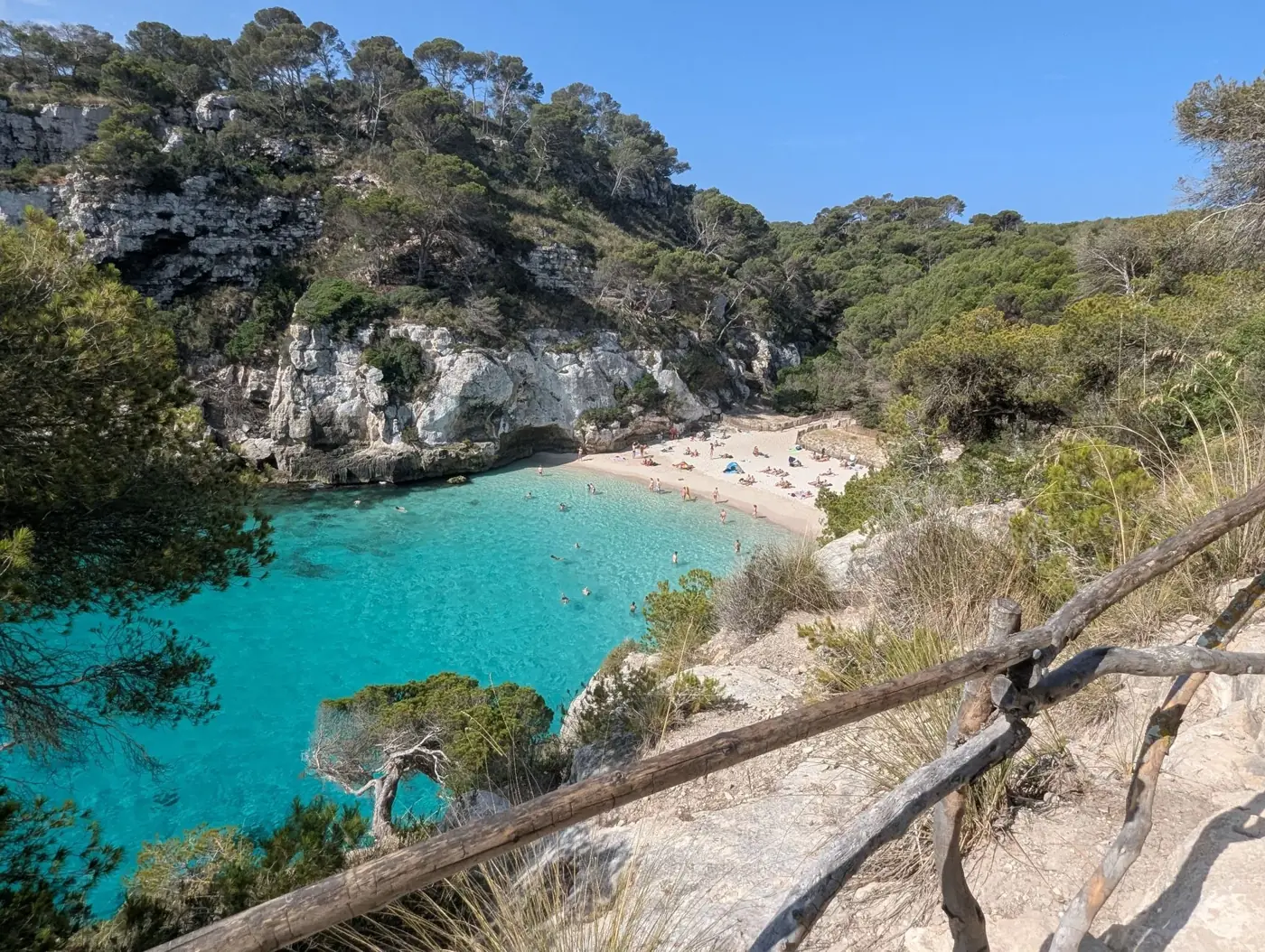 Idyllic beach scene at Cala Macarella, Ciutadella de Menorca, with turquoise water.