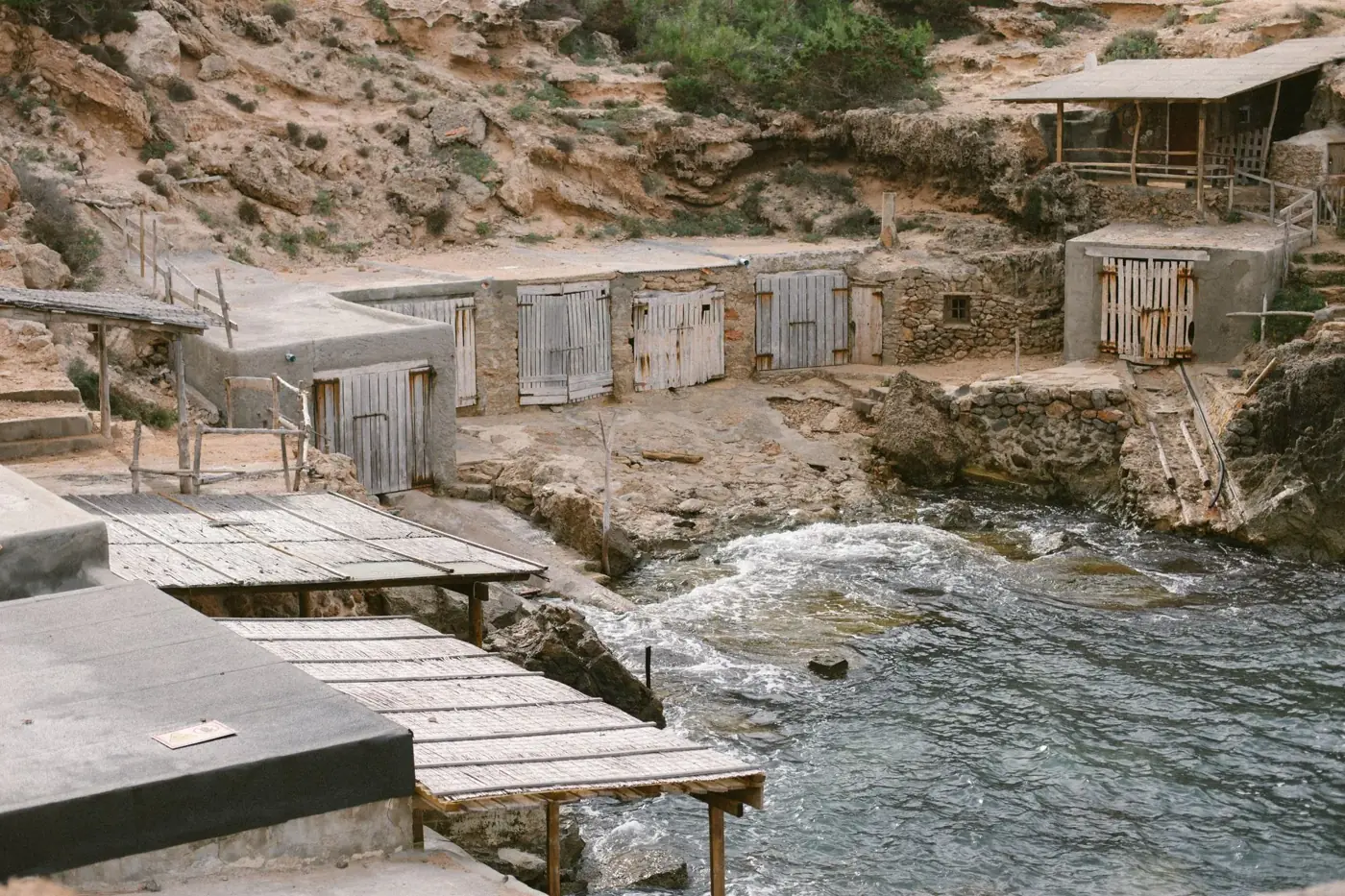 Old rustic fishermen's huts by the rocky coastline in Ibiza, Spain, showcasing Mediterranean charm.
