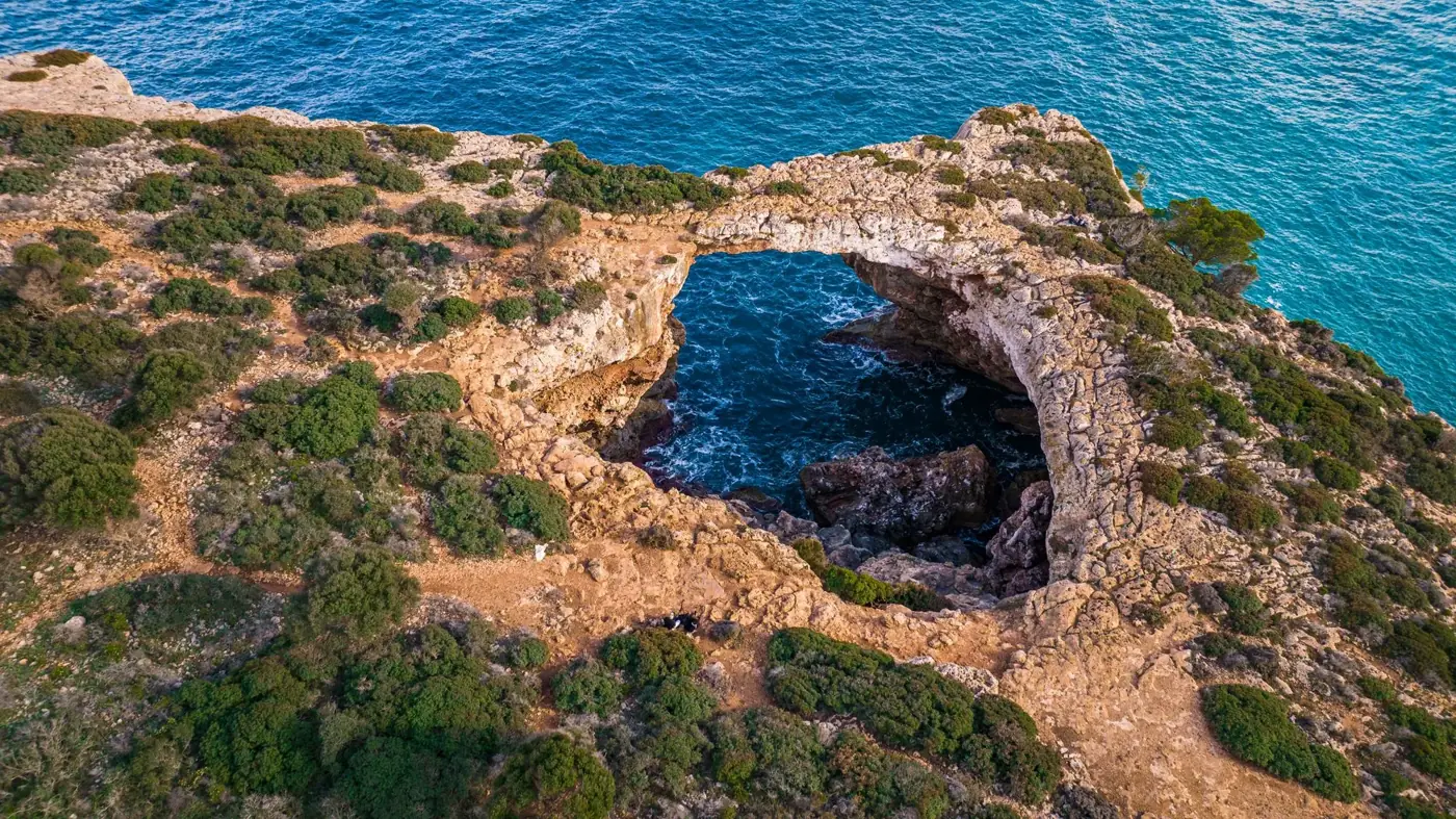 Stunning aerial shot of a natural rocky arch along the coast of Mallorca, Spain.