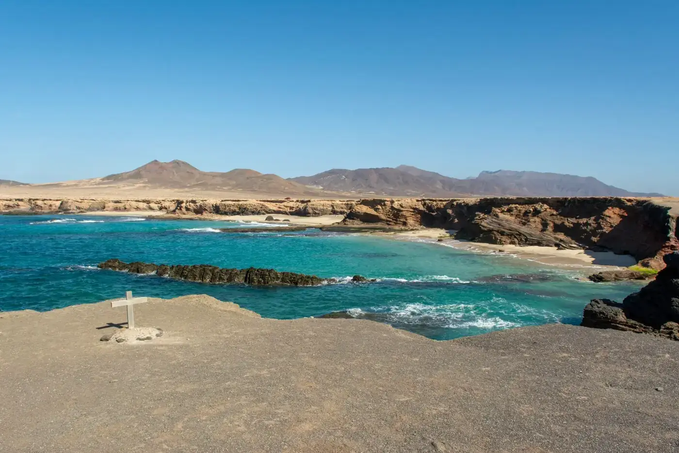 Beautiful view of Fuerteventura's rocky coast and turquoise ocean under a clear blue sky.