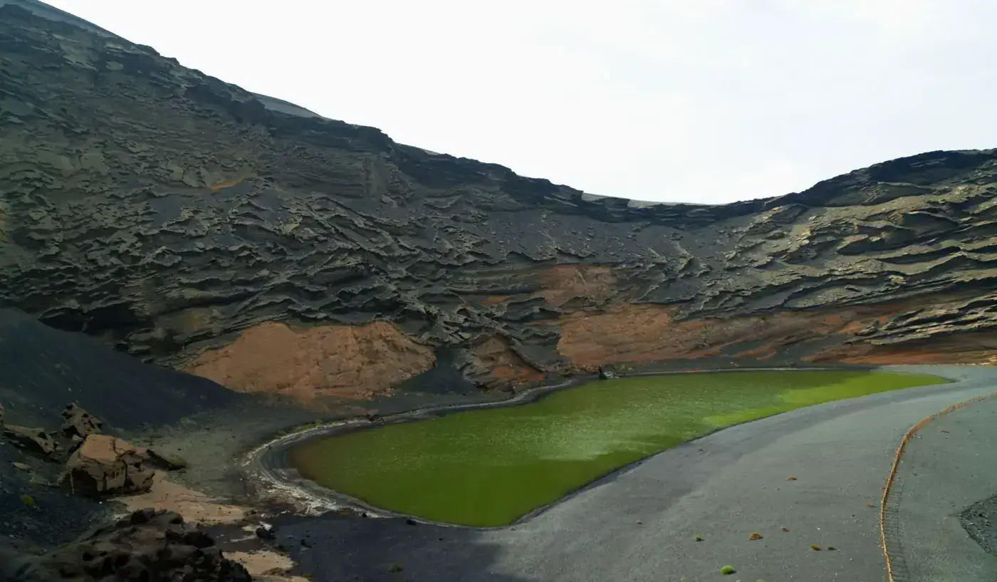 Stunning view of a green crater lake surrounded by volcanic cliffs in Lanzarote.