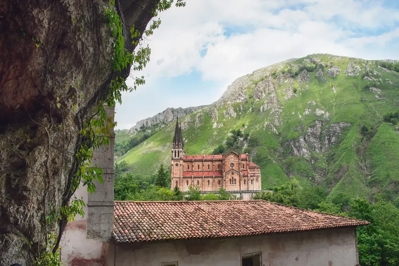 A picturesque view of the Covadonga Church nestled in a lush green valley, surrounded by rocky mountains.