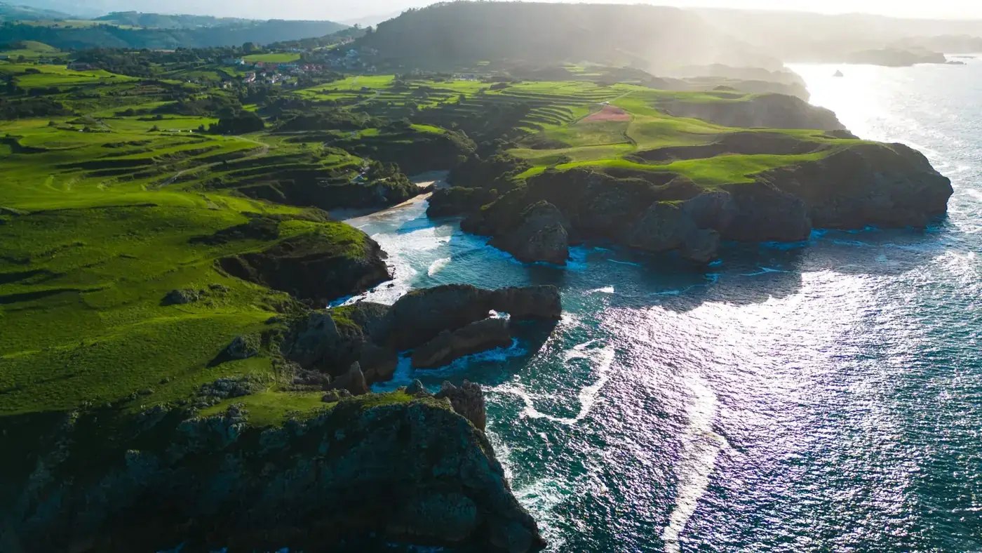 A breathtaking aerial shot of the rugged coastline and lush green landscape of Asturias, Spain.