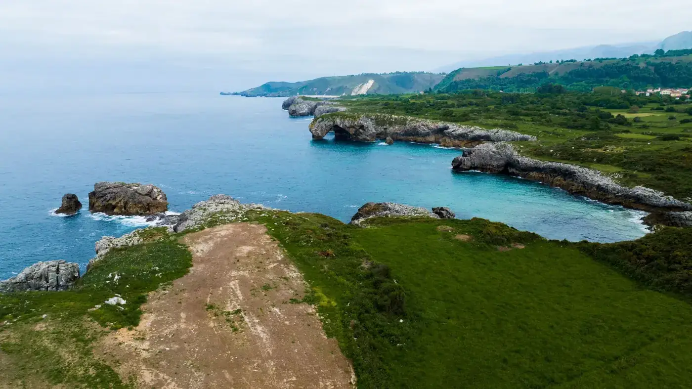 Stunning aerial view of the rocky coastline and cliffs of northern Spain under a cloudy sky.