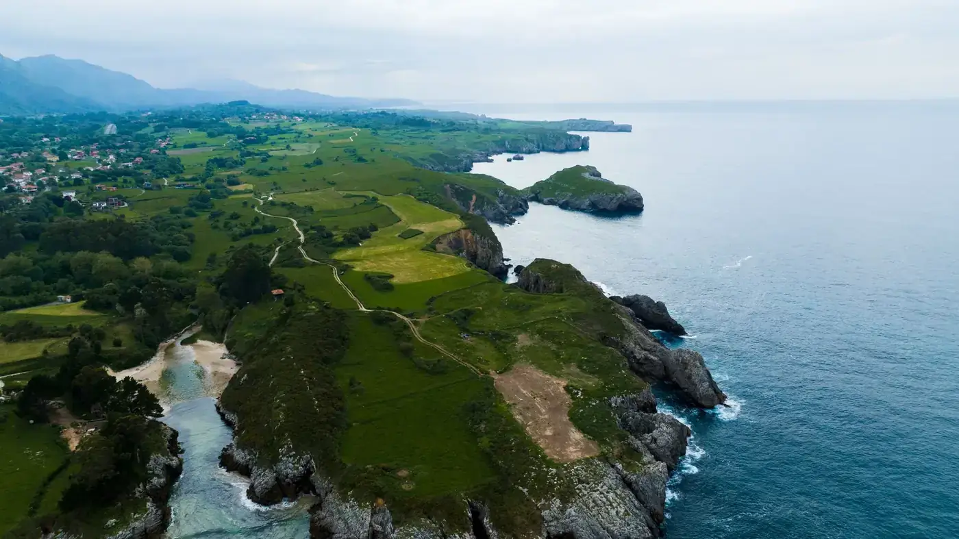 Aerial view of lush coastal cliffs and the sea in Northern Spain.