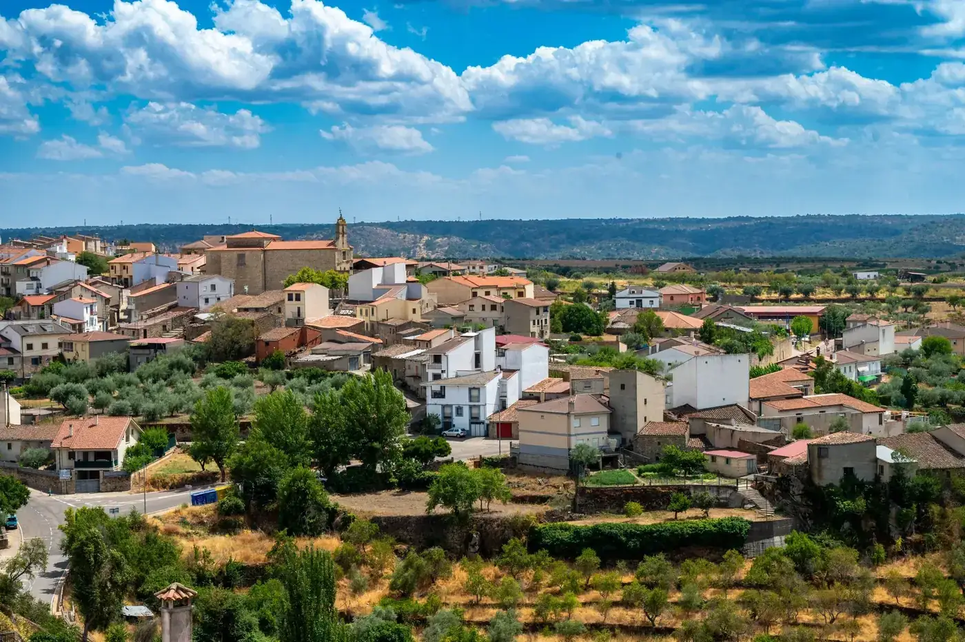 Charming view of a Mediterranean village with rolling hills and lush greenery.