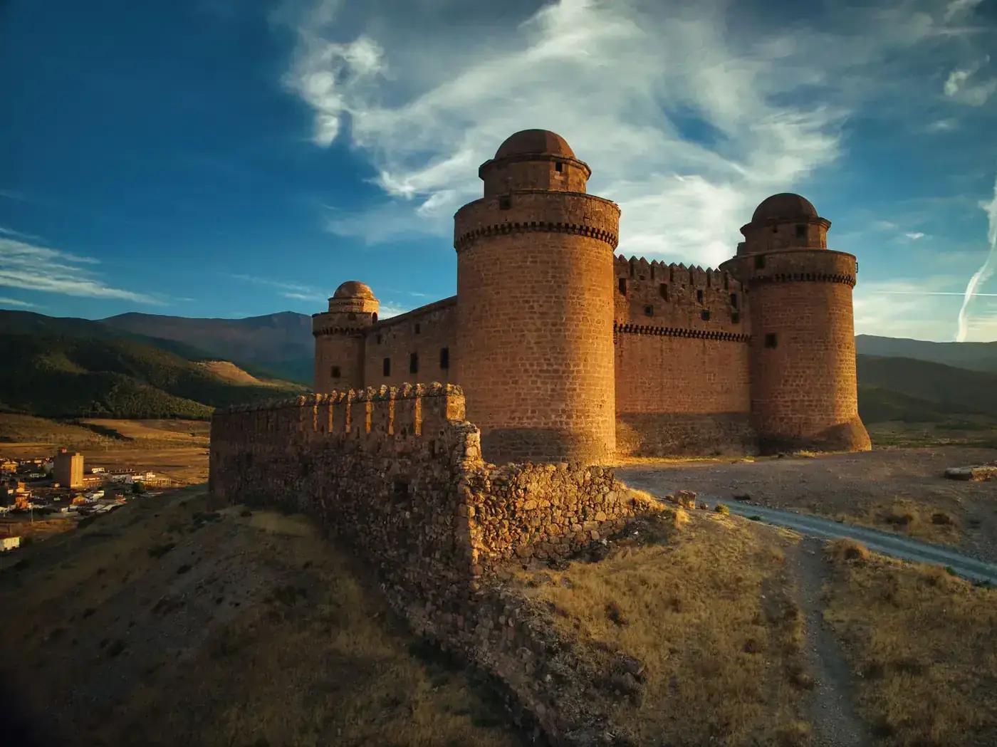 Dramatic view of La Calahorra Castle against a vibrant evening sky in Spain.