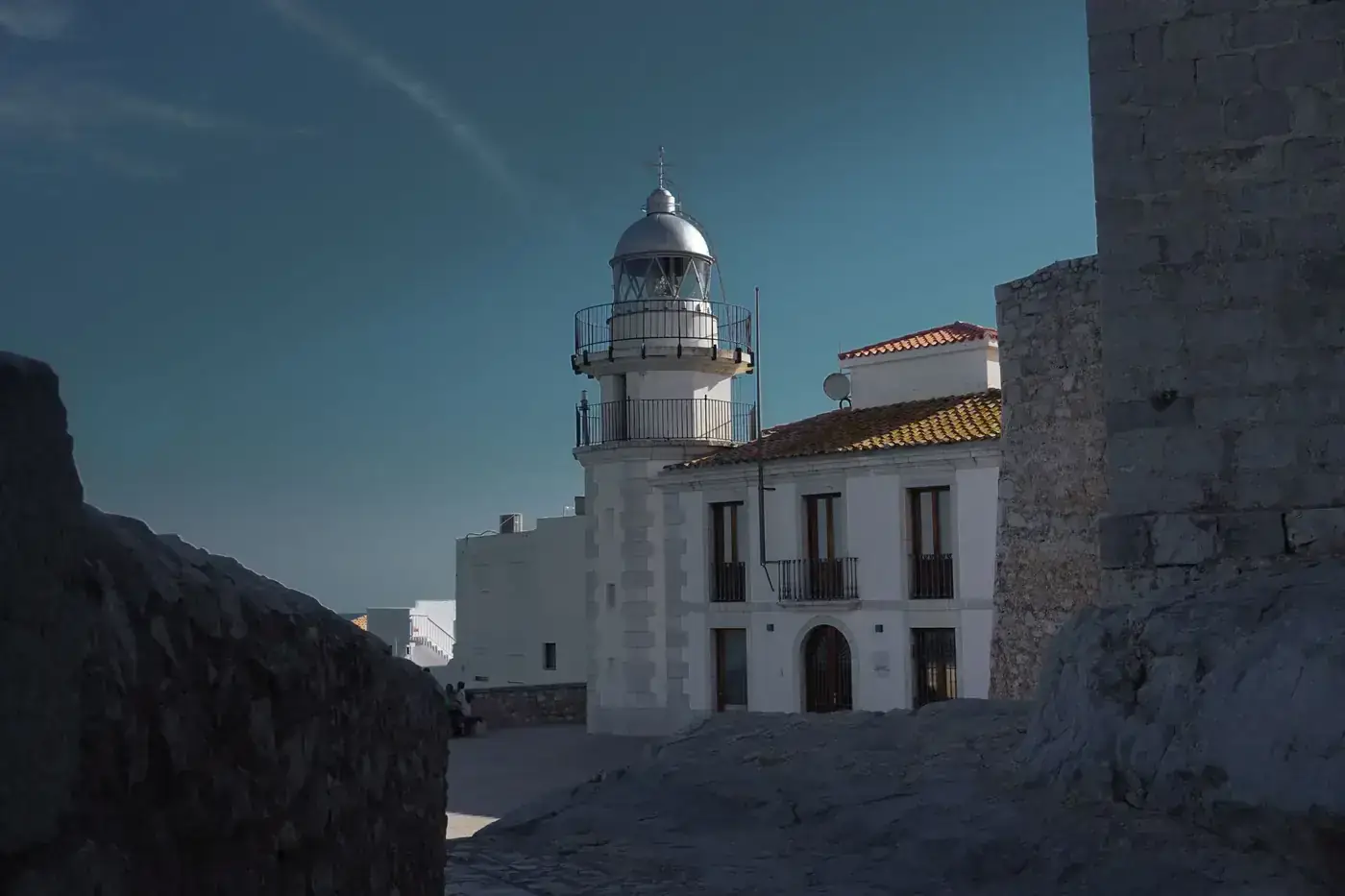 Discover the charming Peñíscola Lighthouse, nestled in a historic Mediterranean town under a bright sky.