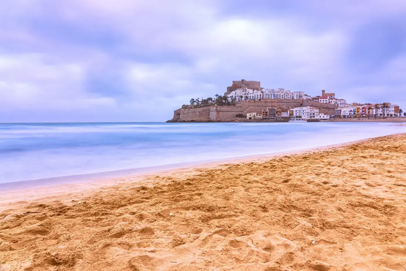 Stunning view of Peñíscola beach and castle against a blue sky.