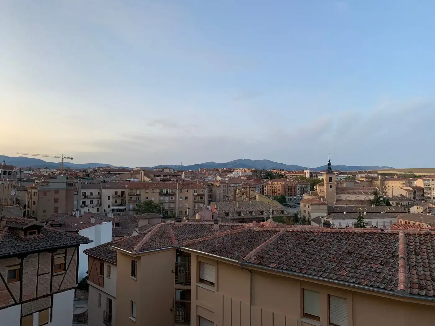 Stunning sunset view of Segovia skyline with historic architecture and mountains in the background.
