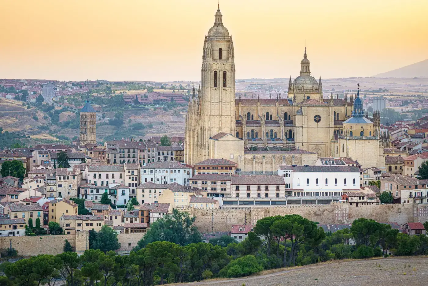 Panoramic view of Segovia Cathedral with a beautiful sunset backdrop, highlighting its architectural grandeur.