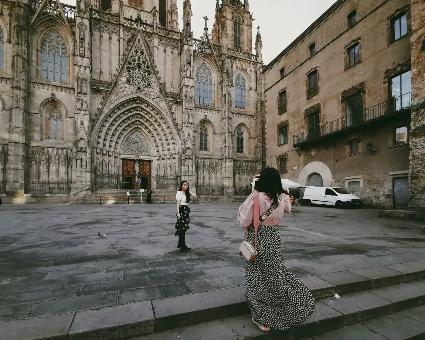 Two women capture the Gothic facade of Barcelona Cathedral, a landmark of Christian heritage in Spain.