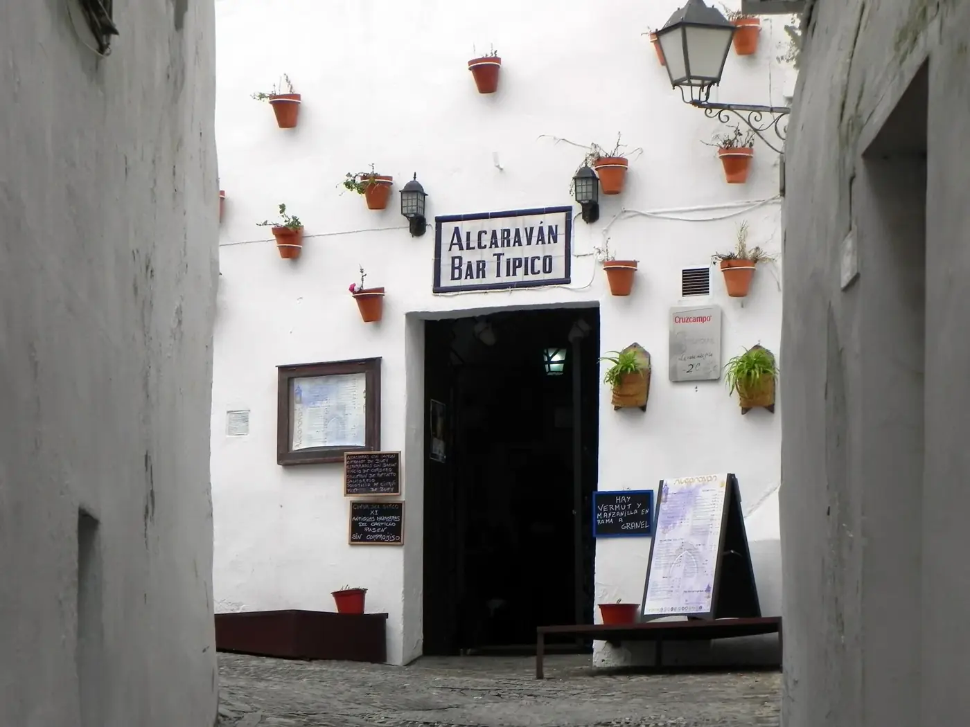 Charming whitewashed alley leading to Alcavarán Bar Típico in Arcos de la Frontera, Spain.