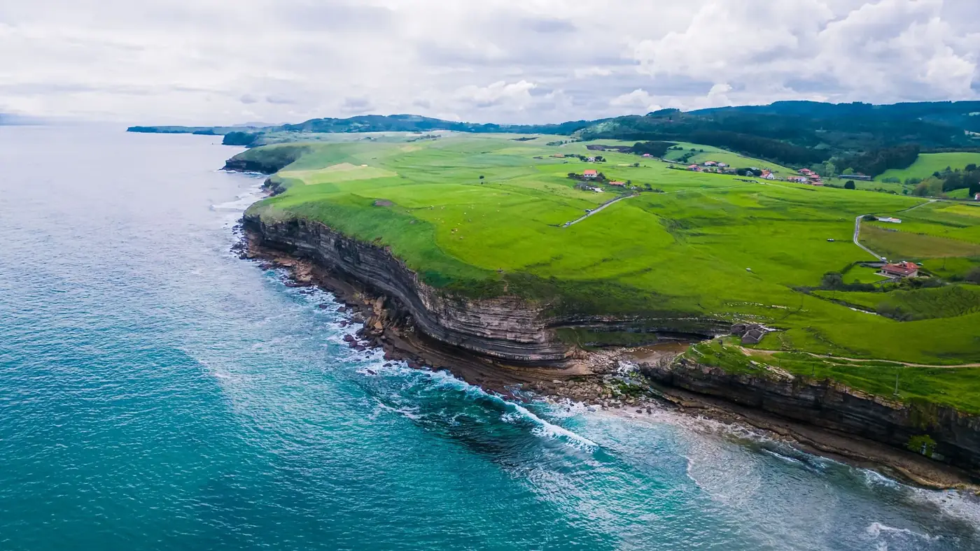 Breathtaking aerial view of Galicia's lush green coastline and cliffs meeting the ocean.