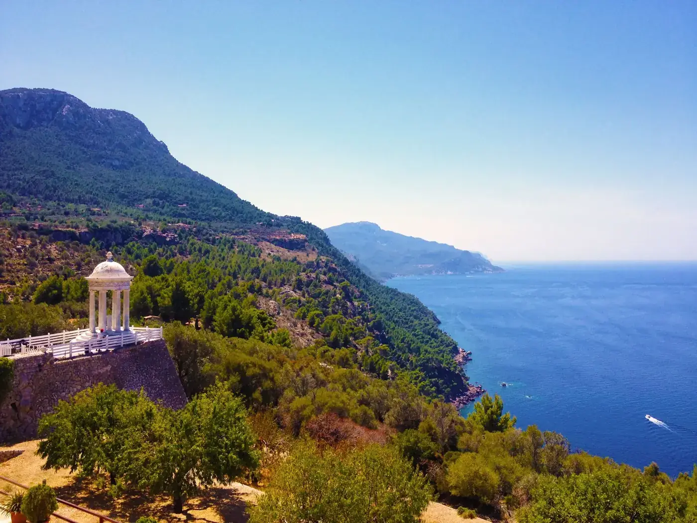 Breathtaking view of Mallorca's coastline featuring a peaceful pergola with lush greenery and azure ocean.