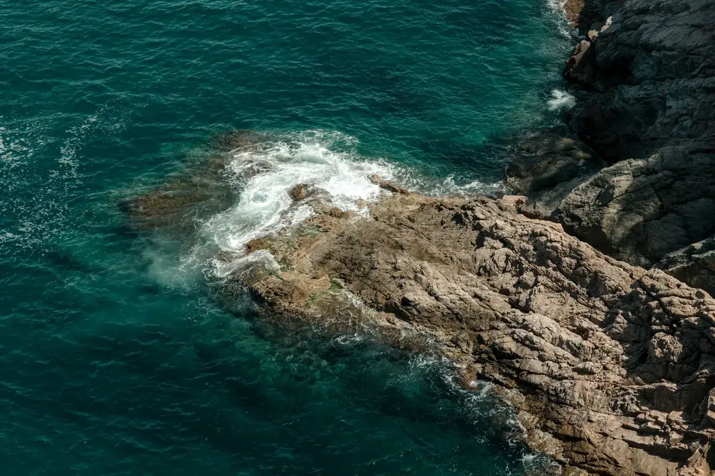 Stunning aerial view of Tossa de Mar's rocky coastline, capturing the vibrant blue sea.