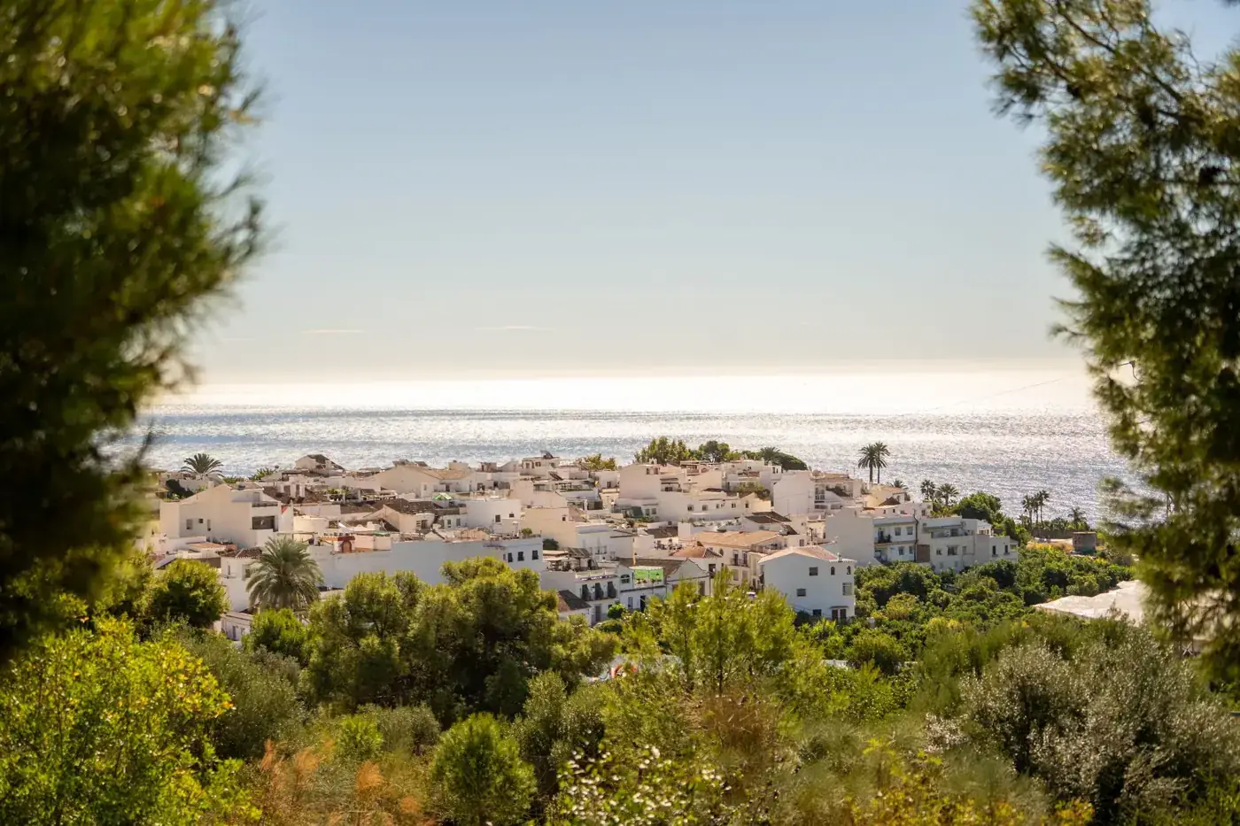 Beautiful coastal view of Nerja, Spain with Mediterranean Sea and whitewashed buildings surrounded by lush greenery.