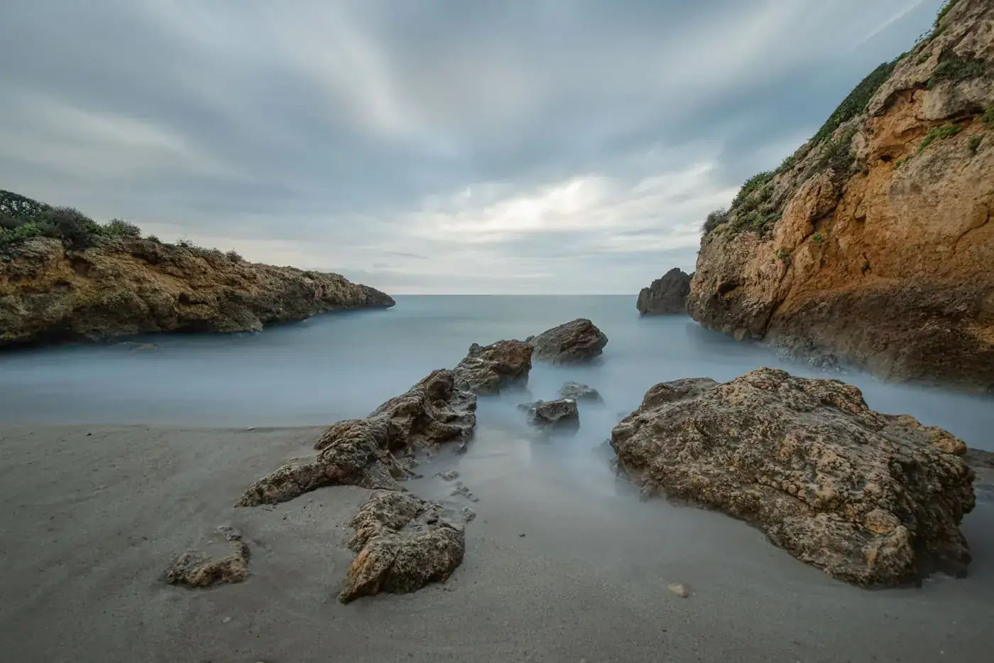 Mesmerizing long exposure of rocky coastline and tranquil sea in CT, Spain.