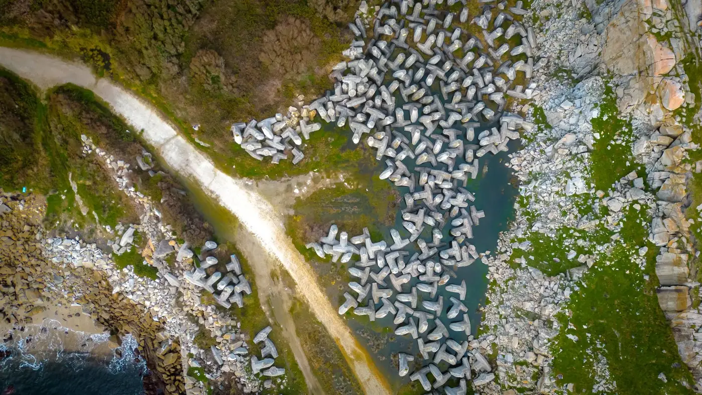 Stunning aerial view of dolos structures along the coast of Lugo, Spain, highlighting the rugged coastline.