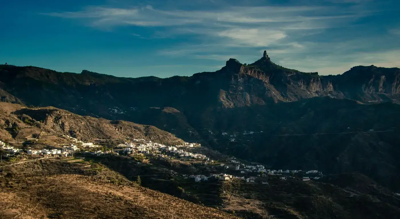 Scenic aerial view of Tejeda village nestled in mountainous terrain in Spain at dusk.