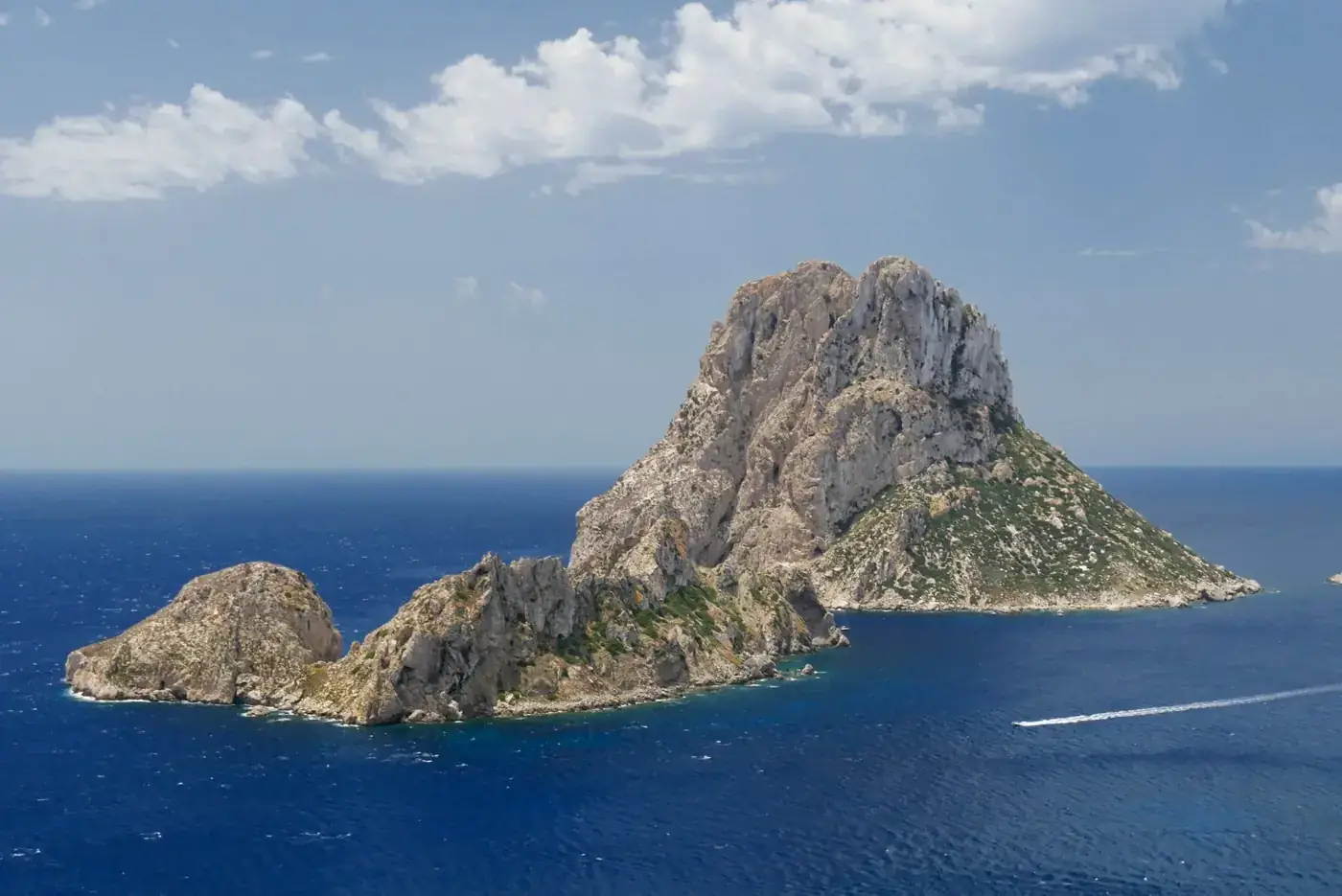 Stunning aerial view of Es Vedrà island surrounded by the Mediterranean Sea under a clear blue sky.