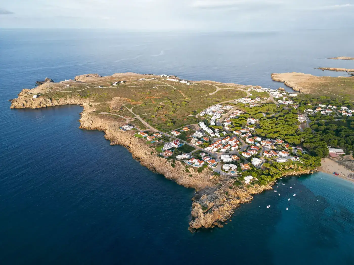 Stunning aerial photo of Arenal d'en Castell coastline in Menorca, Spain, showcasing cliffs and turquoise waters.