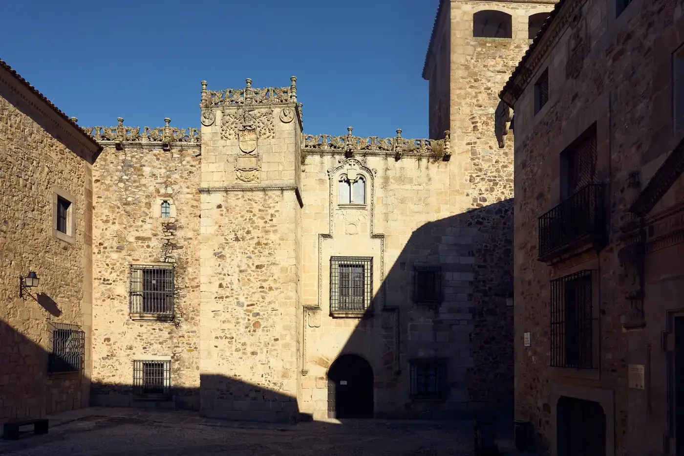 Sunlit stone building in a European courtyard, showcasing medieval architecture.