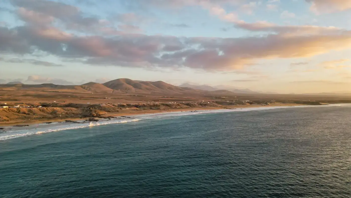Breathtaking aerial view of the serene Spanish coastline and mountains at sunrise with a tranquil sea.