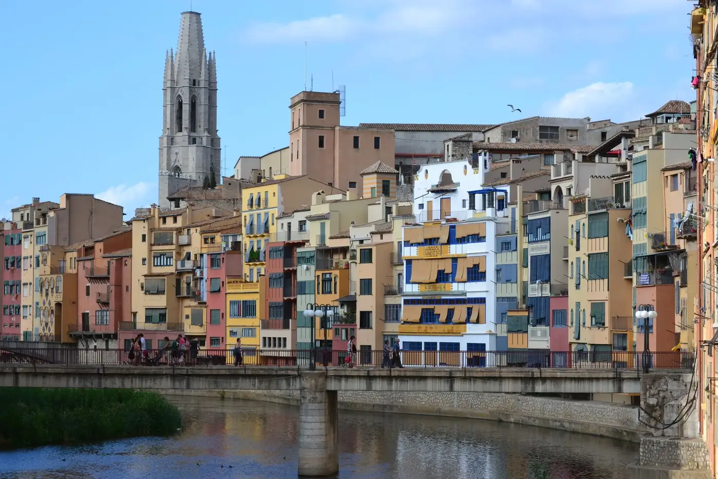 View of vibrant buildings along the Onyar River in Girona, with the Cathedral of Girona in the background.