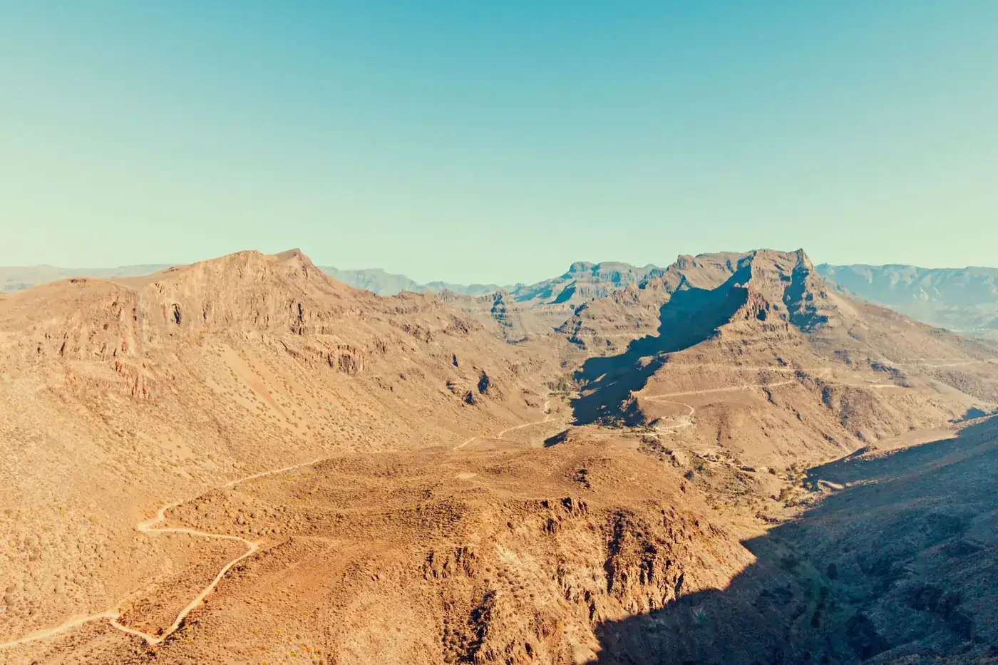 Breathtaking aerial view of a desert valley with rugged terrain and clear skies.