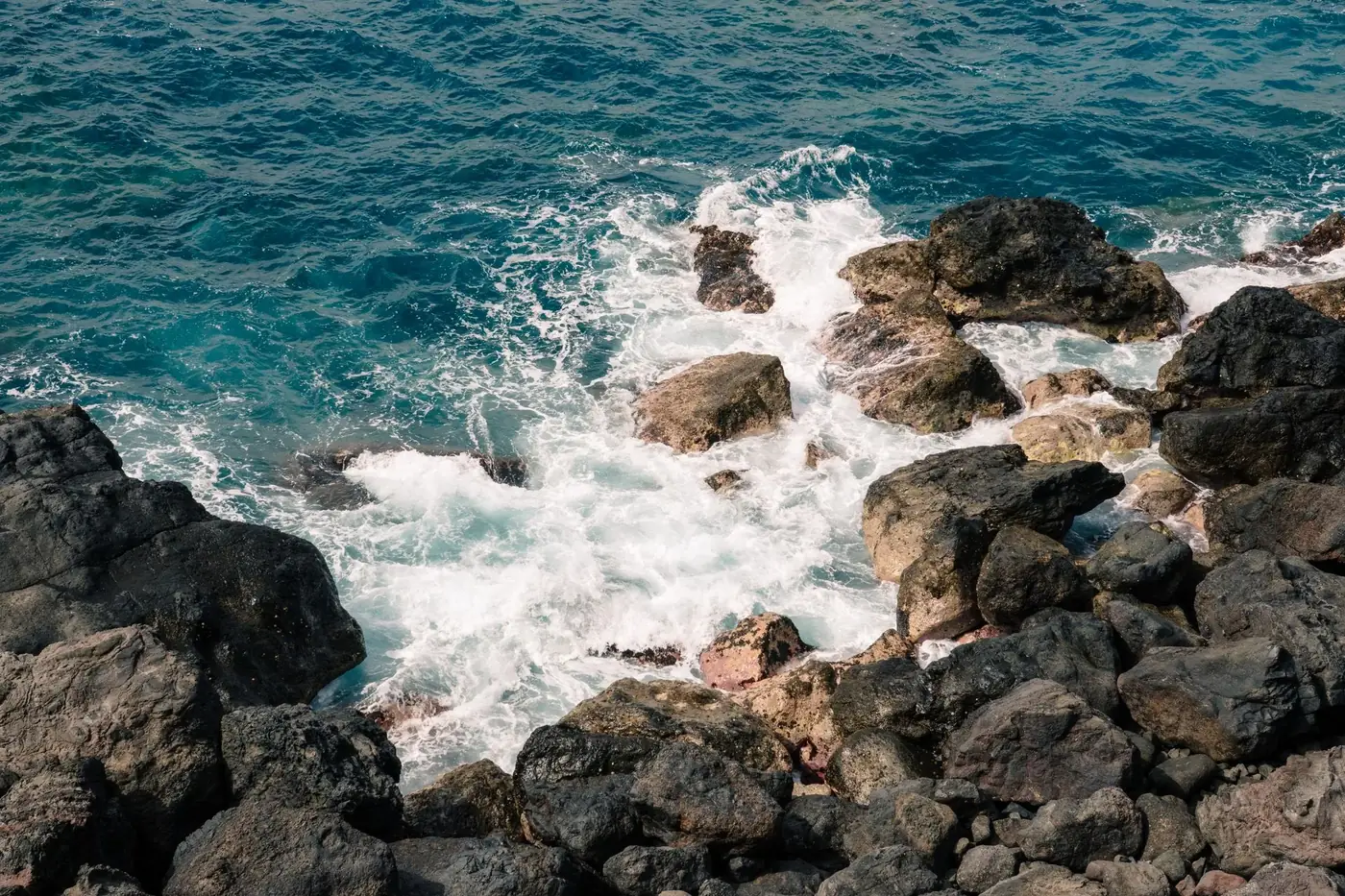 Powerful waves crashing on rugged volcanic rocks at Santa Catalina, Spain, creating a dynamic ocean scene.