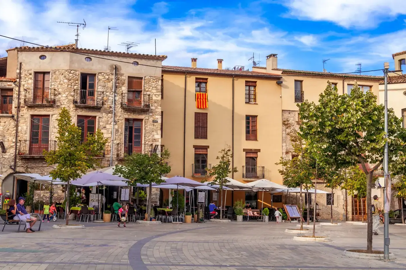 Picturesque square in Besalú, Spain, showcasing historic architecture and vibrant outdoor cafes.