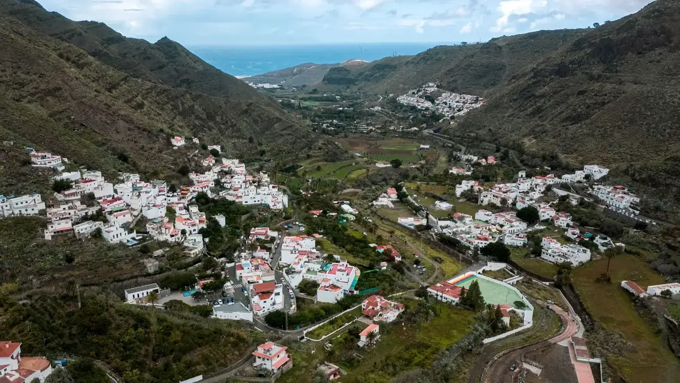 Stunning aerial view of a village nestled in the Canary Islands, surrounded by lush mountains and the sea.