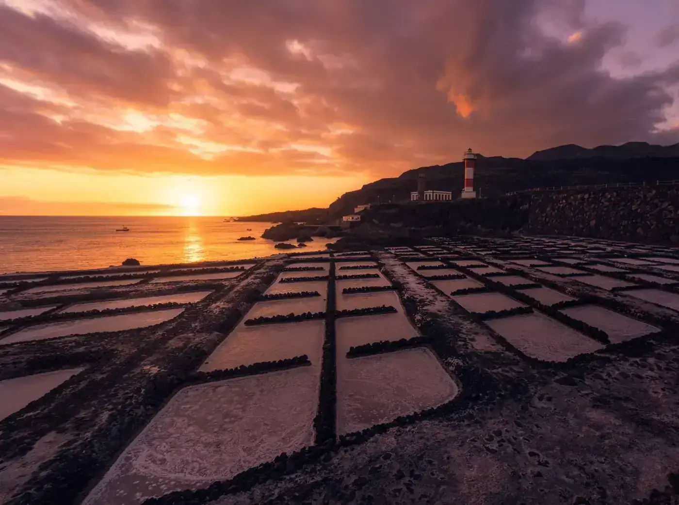 Gorgeous sunset view of Salinas de Fuencaliente with the iconic lighthouse casting a dramatic silhouette.